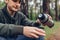 Man tourist pours hot tea out of thermos in autumn forest. Camping, traveling and sport concept