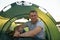 Man tourist sitting inside camp tent. Male spending holiday with tent near lake