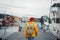 Man tourist with touristic rucksack wearing yellow jacket walking among authentic fishing boats