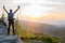 Man tourist with trekking poles on top of hill at sunrise