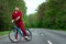 A man in a tracksuit on a bicycle rides on a road in the forest. The concept of a healthy lifestyle, cardio training. Copyspace