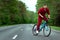 A man in a tracksuit on a bicycle rides on a road in the forest. The concept of a healthy lifestyle, cardio training. Copyspace