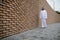 A man in traditional arabian headwear standing near the brick wall