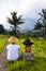 Man with traditional balinese cap by small altar at rice fields of Jatiluwih in southeast Bali