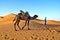 Man in traditional berber wear eads a camel