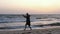 Man training Chinese martial art Taijiquan at sea beach, evening sky background