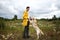 Man training Labrador Retriever on green meadow