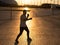 A man trains in boxing at the stadium at sunset. Athlete silhouette.