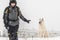 Man trains sitting dog in the winter in the snow