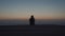 Man traveler with backpack admires the view of sunset and the mediterranean sea from wooden pier on island of cyprus