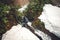 Man Traveler with backpack crossing waterfall and snow glacier