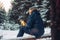 Man traveler forester hunter in the winter forest sitting on fallen tree