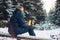 Man traveler forester hunter in the winter forest sitting on fallen tree