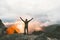 Man traveler happy raised hands on mountain top