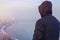 Man traveler in hood looking at winter city landscape