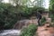 A man, a traveler in a leather jacket and a cowboy hat. Large full-flowing waterfall with dirty water, a journey, a place for text