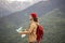 Man Traveler with map and red backpack searching location outdoor with rocky mountains on background