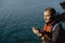 Man traveler in a red waistcoat watching world map on mobile phone while relaxing near sea