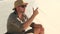 man traveler in safari clothes sits on sand dune in the desert and drinks water