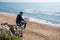 Man traveler watching city map while relaxing near ocean during his trip