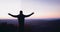 A man, traveller enjoys the majestic view on mountains in morning light. raising hands, welcoming a new day