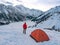A man travels in the mountains in winter. A man and a tent on the background of a frozen mountain lake