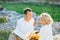 Man treats woman to food while sitting on a blanket in autumn forest