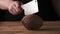 Man tries to chop a coconut on the table. Black background