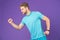 Man in tshirt and shorts on violet background. Runner in blue casual clothes on purple background. Sportsman in active wear for ru