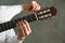 Man tunes classic guitar against dark background