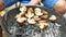 Man turn over large delicious champignon mushrooms, which roast over the coals on barbecue.