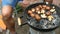 Man turn over large delicious champignon mushrooms, which roast over the coals on barbecue.