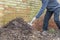 Man turning a compost heap in a garden, UK