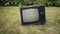 Man turns on old retro TV set standing on grass. Then person knocking the device