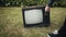 Man turns on old retro TV set standing on grass. Then person switches channels