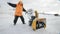 Man turns on a snow thrower in winter in an orange jacket