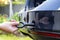 A man twists a towing eyelet into a passenger car to pull the car out of the mud, close-up