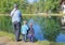 a man and two children fishing. Father and two sons fishing, trout at a trout farm. Children watch as fish..
