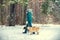 A man with two dogs on leashes walking in winter forest