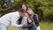 Man with two kids embracing pregnant women outdoors. Handsome man and two cute sisters embracing pregnant tummy of