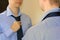 Man tying necktie standing in front of mirror