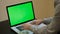 A man types on a laptop. Young Handsome Man Sits and Works on Green Screen Laptop