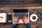 Man typing laptop on wooden desk