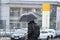 A man with an umbrella in the rain crossing the road.