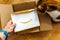 Man unboxing Amazon.com cardboard containing a surprise envelope