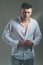 Man unbutton fashionable shirt. Young macho undress white shirt. Guy with serious face. model with elegant casual