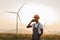 Man in uniform talking on mobile on farm with wind turbines