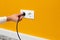 Man unplugging cord from a electrical outlet