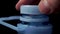 Man unscrews the blue plastic cap of a large plastic water bottle on a black background.