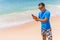 Man use phone on the beach typing or use internet on sunny day